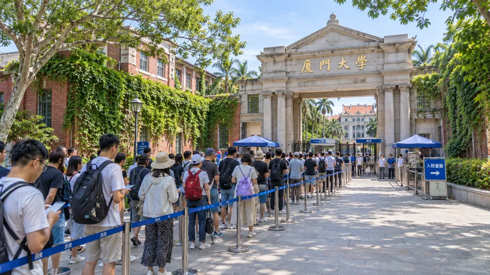 廈門大學校門前的通道，數十名旅客手持身分證排隊等待入校查驗，牆面爬滿綠藤